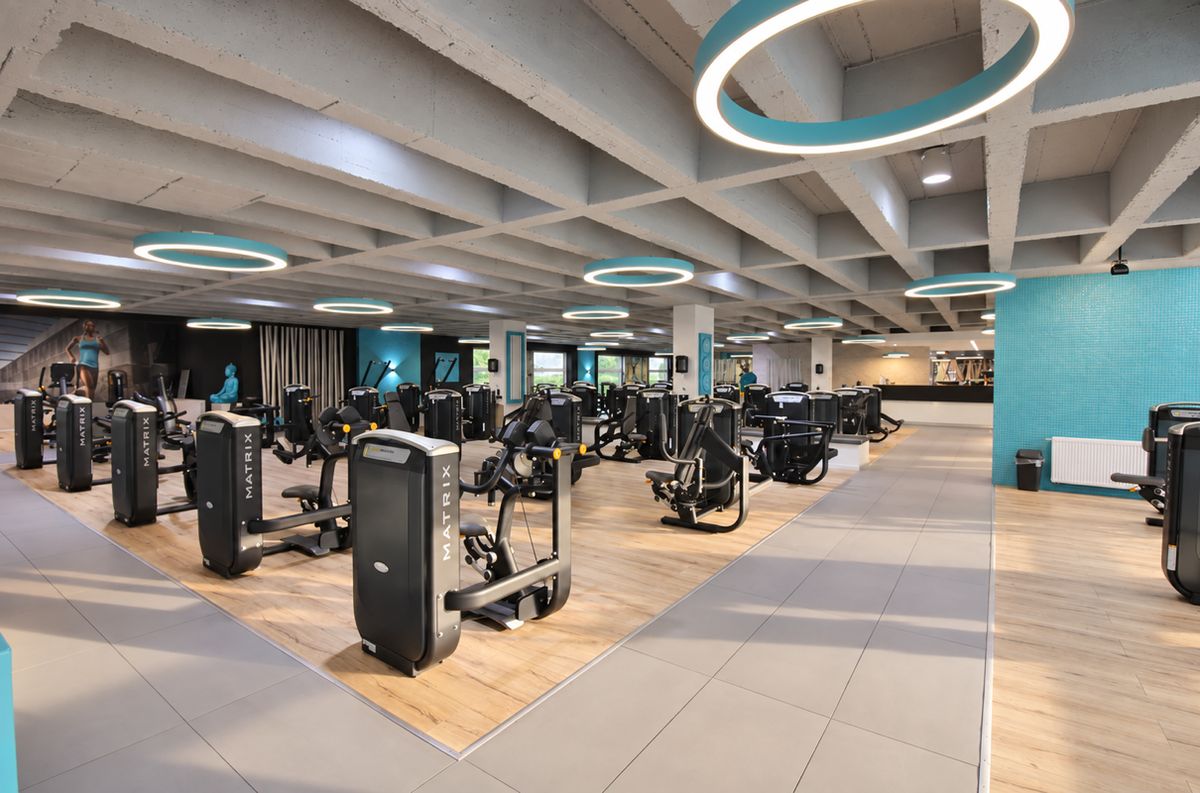 Große Trainingsfläche des VitaLounge Fitnessstudios mit Kraftgeräten und türkisfarbenen Akzenten