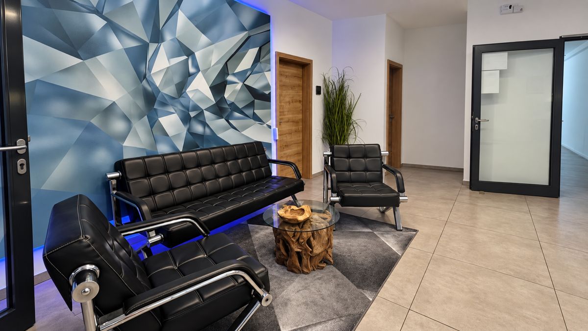 Lounge mit schwarzem Ledersofa vor geometrischer Wandgestaltung