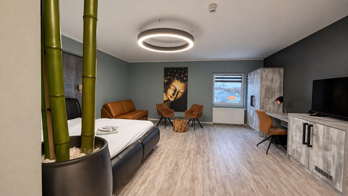 Zimmer mit Bambus-Dekoration, Bett und Sessel aus Cognac-Leder