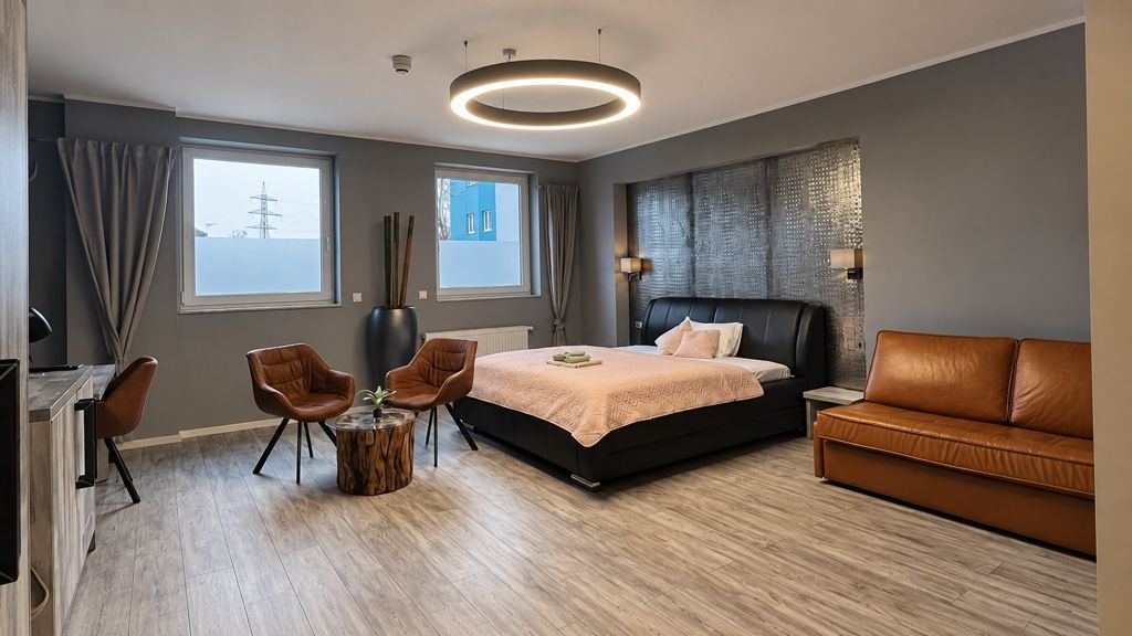 Zimmer mit Sofa aus Cognac-Leder, Bett und Lichtring